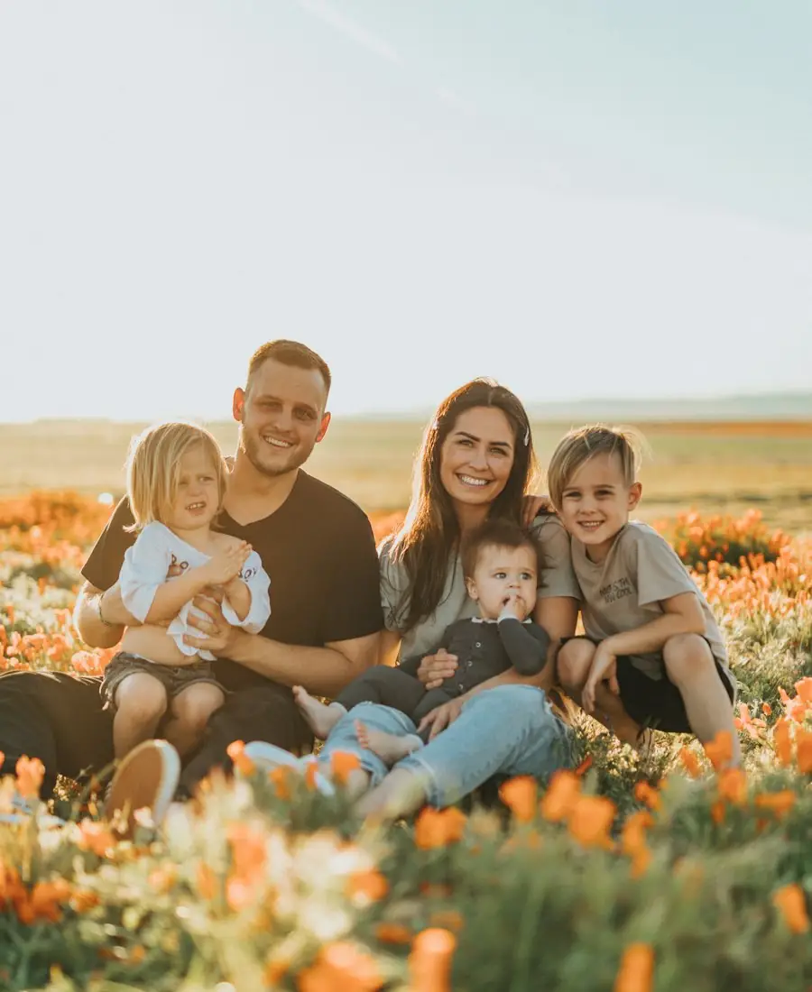 Family smiling while sitting in a field of flowers